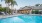 a swimming pool with chairs and a house in the background